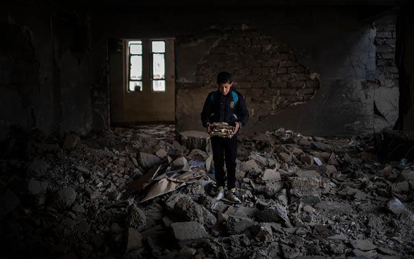 12-year-old Yousef holds destroyed schoolbooks at Jummuria Secondary School in Mosul, Iraq.
The school was severely damaged by shelling during the war in Mosul. Yousef dreams of becoming a police officer.