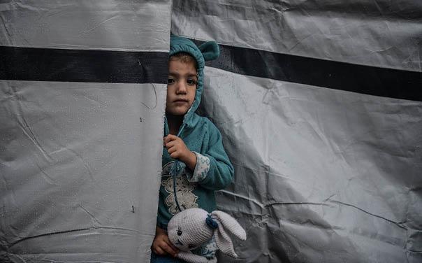 Et barn halvveis bak en teltduk i Khan Younis i Gaza.