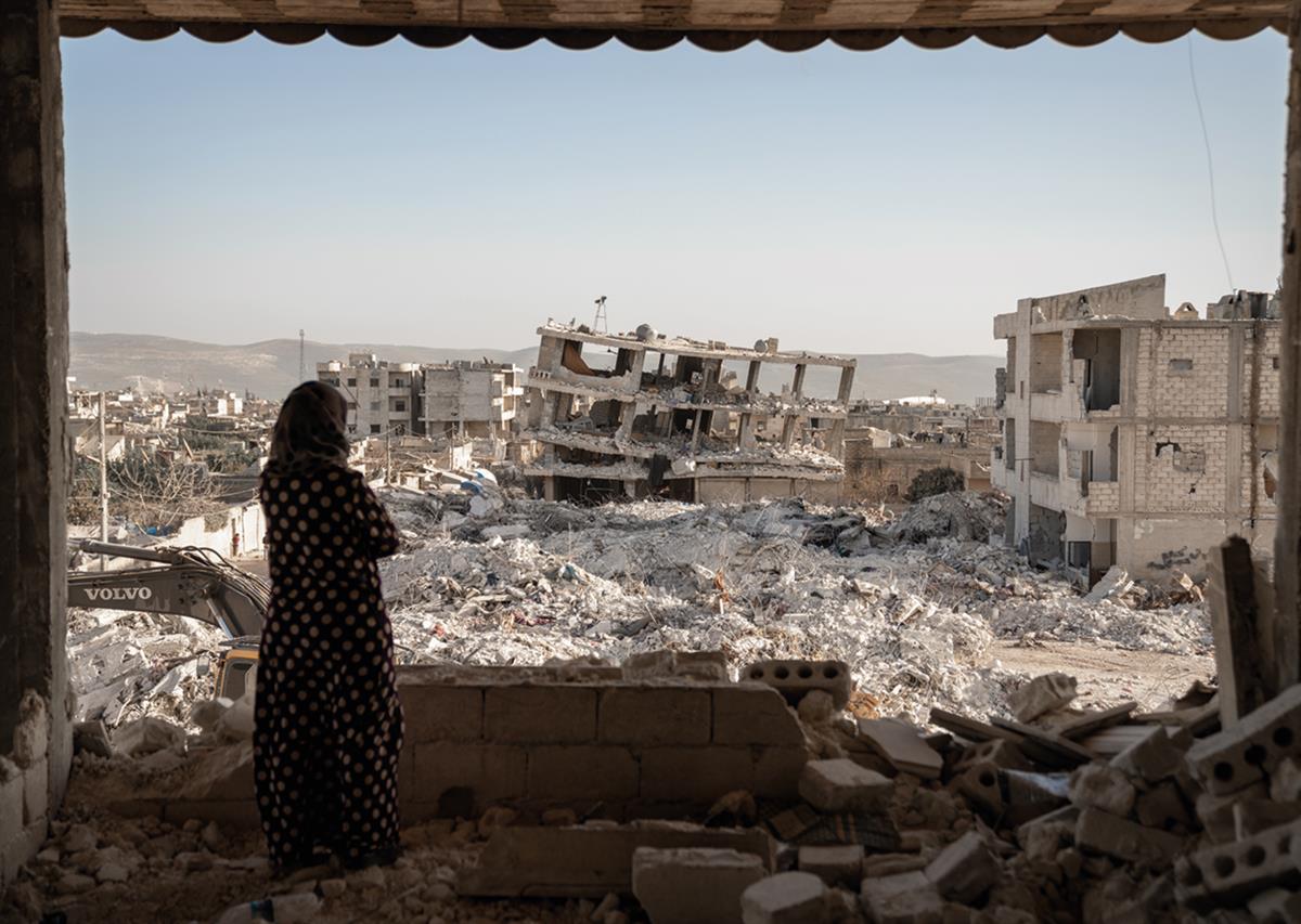 En kvinne ser ut over ødeleggelsene av byen Jinderis i Aleppo-regionen etter jordskjelvene som rammet Syria og Tyrkia i 2023.