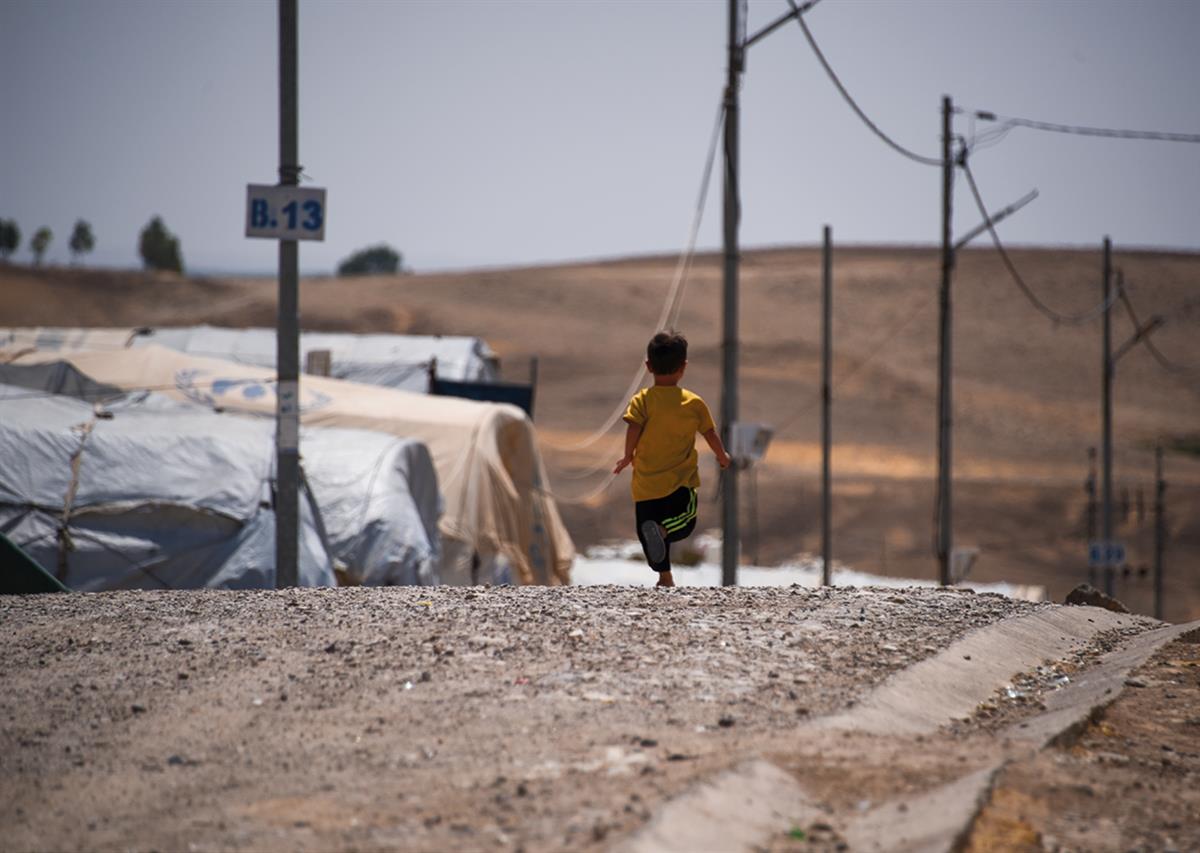 En ung gutt som løper nedover en vei i Bardarash flyktningleir for syriske flyktninger i Irak.