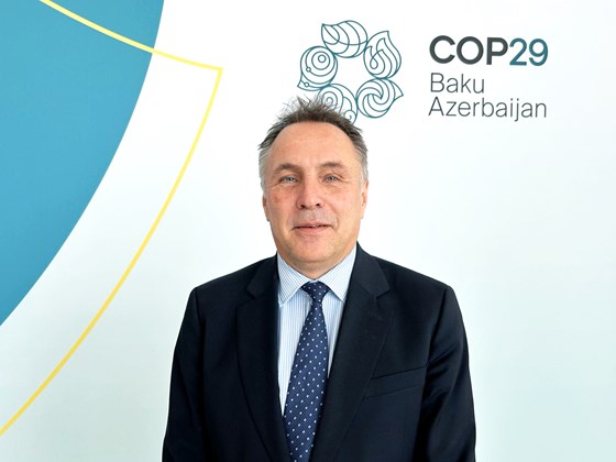 Klima- og miljøminister Tore O. Sandvik står foran en hvit bakgrunn med teksten "COP29 Baku, Azerbaijan".