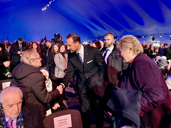 Statsminister Erna Solberg og HKH Kronprins Haakon hilser på Edith Notovizc, som overlevde konsentrasjonsleiren Auschwitz-Birkenau.