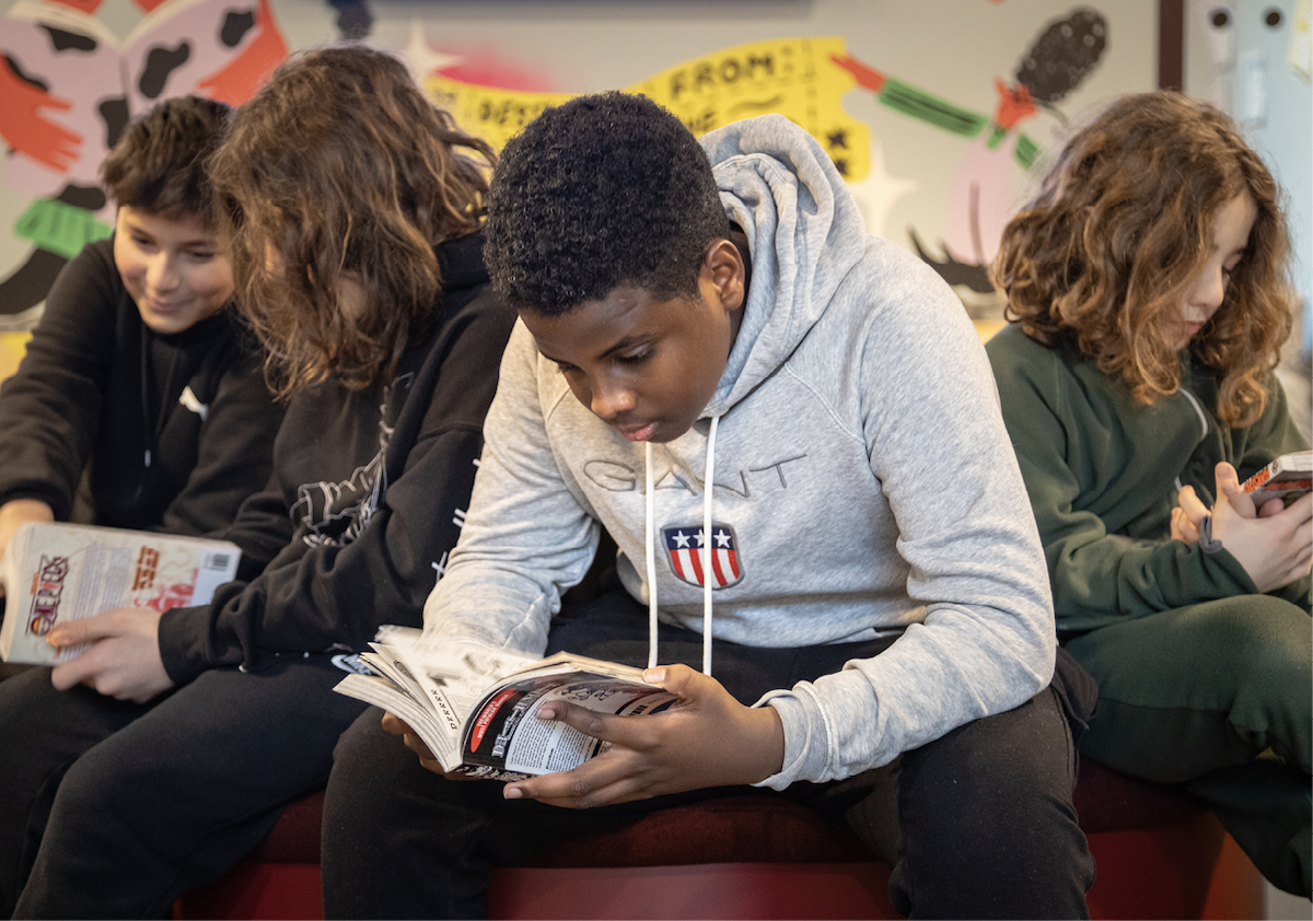 Fire ungdommer leser forskjellige bøker i et bibliotek