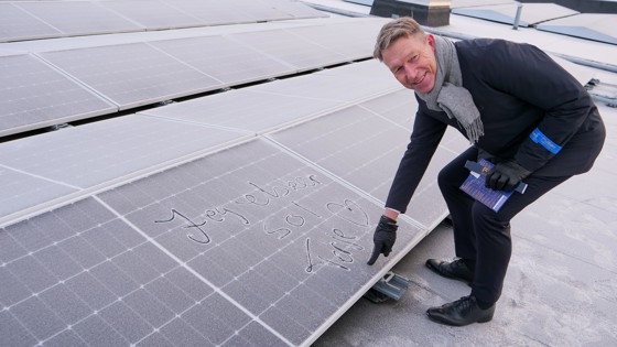 Energiminister Terje Aasland signerer et solcellepanel på taket av Alna Senter