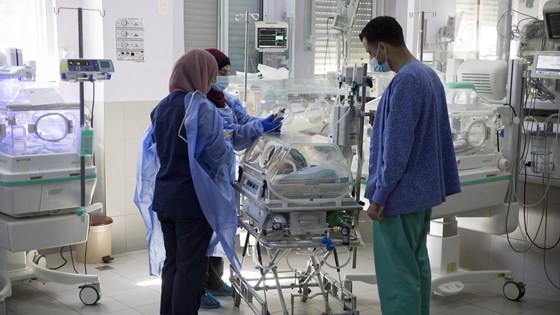 Bilde av tre sykepleiere ved kuvøse på sykehys