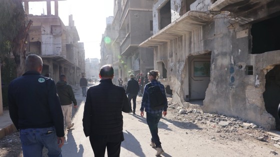 People walking between destroyed buildings