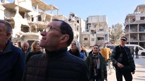 People walking between destroyed buildings