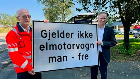 Samferdselsminister Jon-Ivar Nygård og Halvard Gavelstad fra Statens vegvesen holder skilt med teksten «Gjelder ikke elmotorvogn man–fre»