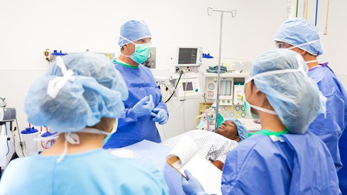 Lege og legestudenter står rundt en pasient.