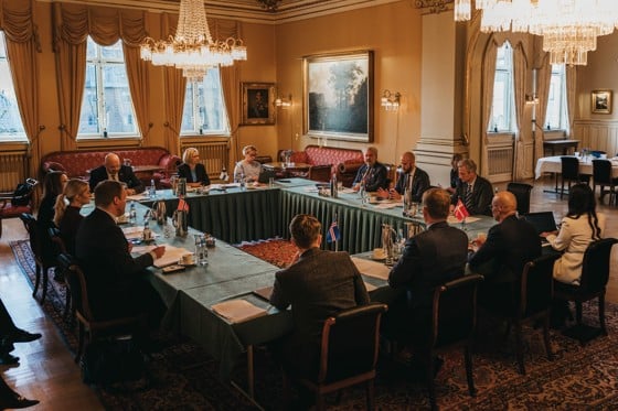 A large room with several people around a horseshoe shaped table.