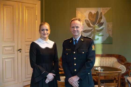 Mann i blå uniform ved siden av kvinne i formelle klær.