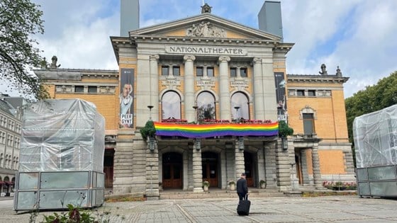 Fasaden til Nationaltheatret med pridebanner og innpakkede statuer foran hovedinngangen.