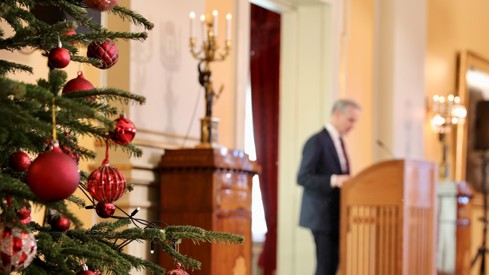 Statsminister Jonas Gahr Støre står ved talerstolen. Juletre med røde julekuler i forgrunnen.