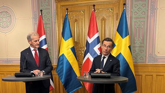 Jonas Gahr Støre med Sveriges statsminister Ulf Kristersson foran svenske og norske flagg.