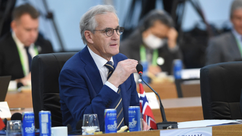 Prime Minister Støre sitting at a big conference table in Rio de Janeiro.