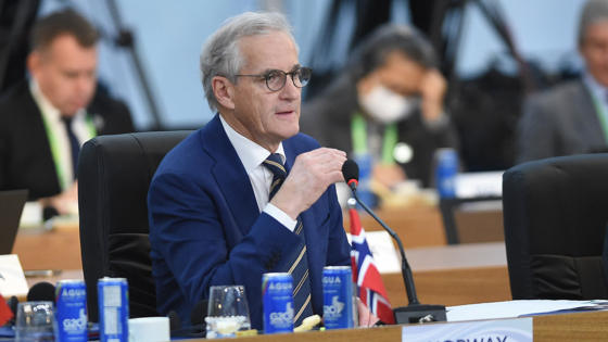 Prime Minister Støre sitting at a big conference table in Rio de Janeiro.