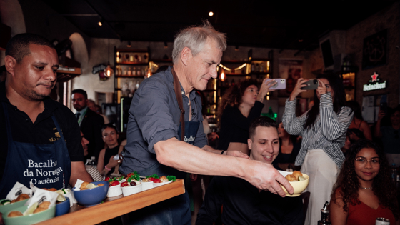 Prime Minister Støre serving bacalao in a crowded restaurant in Rio de Janeiro. 