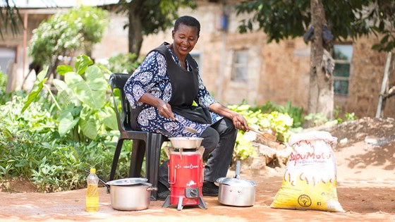 Kvinne som sitter ved en mobil komfyr for å lage mat.
