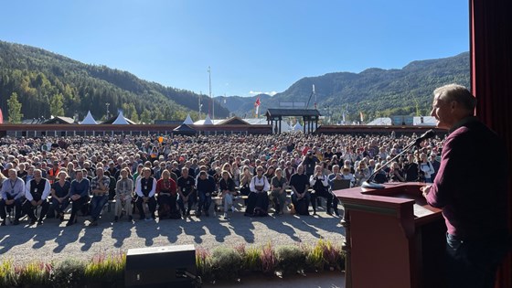 Statsministeren ser ut over folkehavet på Dyrsku'n i Telemark. Han står bak en talerstol med ryggen til kamera.