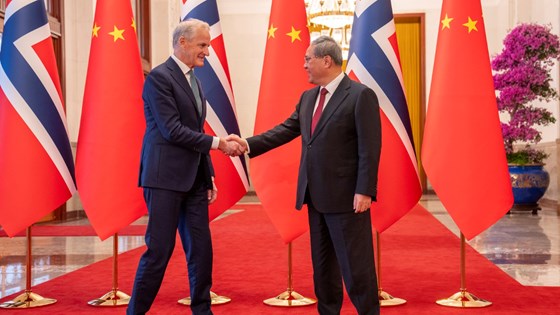 Handshake-photo. Chinese and Norwegian flags behind Støre and Li Qiang. 