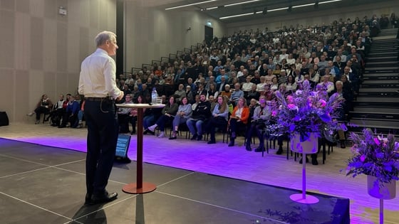 Statsministeren står på en scene, foran et fullt auditorium i Kristiansund.