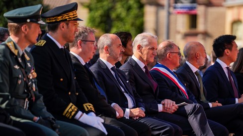 Forsvarssjefen, forsvarsministeren og statsministeren sitter på stoler sammen med andre gjester i Normandie.