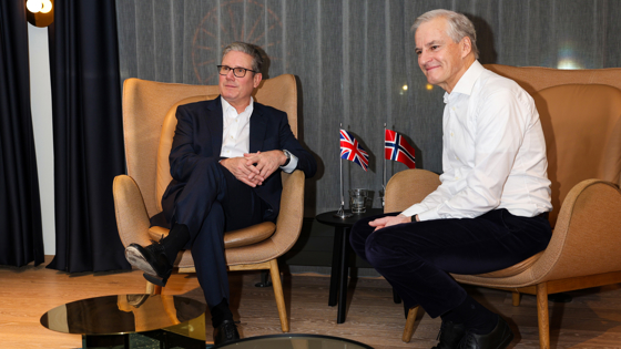 The prime ministers's are sitting in chairs, with at little table in between. With table flags from UK and Norway.