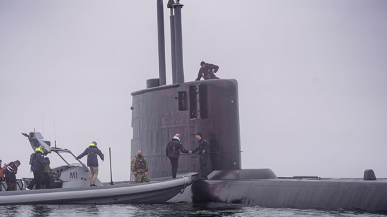 Statsminister Jonas Gahr Støre på vei over fra en plastbåt til ubåten KNM Utvær, som ligger på vannet.