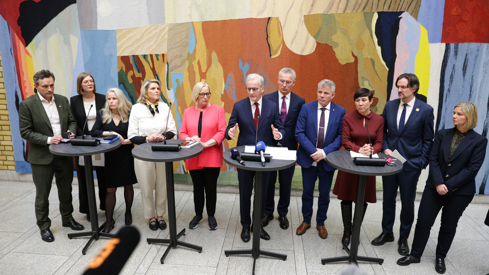 Representanter for alle partiene på Stortinget står ved siden av hverandre i Vandrehallen.