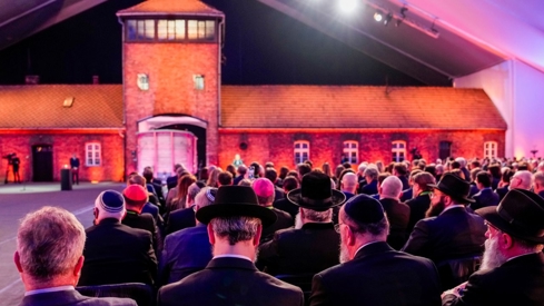 The famous building in Aschwitz. A crowd in front, sitting in chairs.