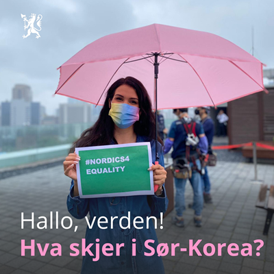 Jente med langt brunt hår står med en rosa paraply og et fargerikt munnbind med en plakat til støtte for PRIDE, i Soul i Sør-Korea.