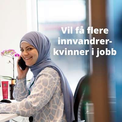 Kvinne med hijab sitter på kontor i telefonen og smiler